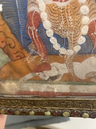 A Tibetan thangka in inlaid gilt brass frame, 19th C.